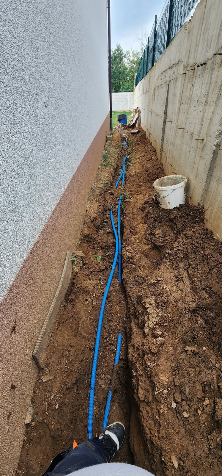 Tubacione blu të ujit të shtruara në kanal pranë objektit